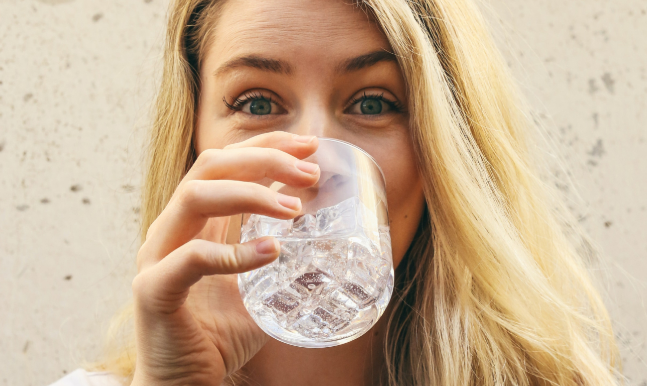 Фото девушки, пьющей воду из стакана.