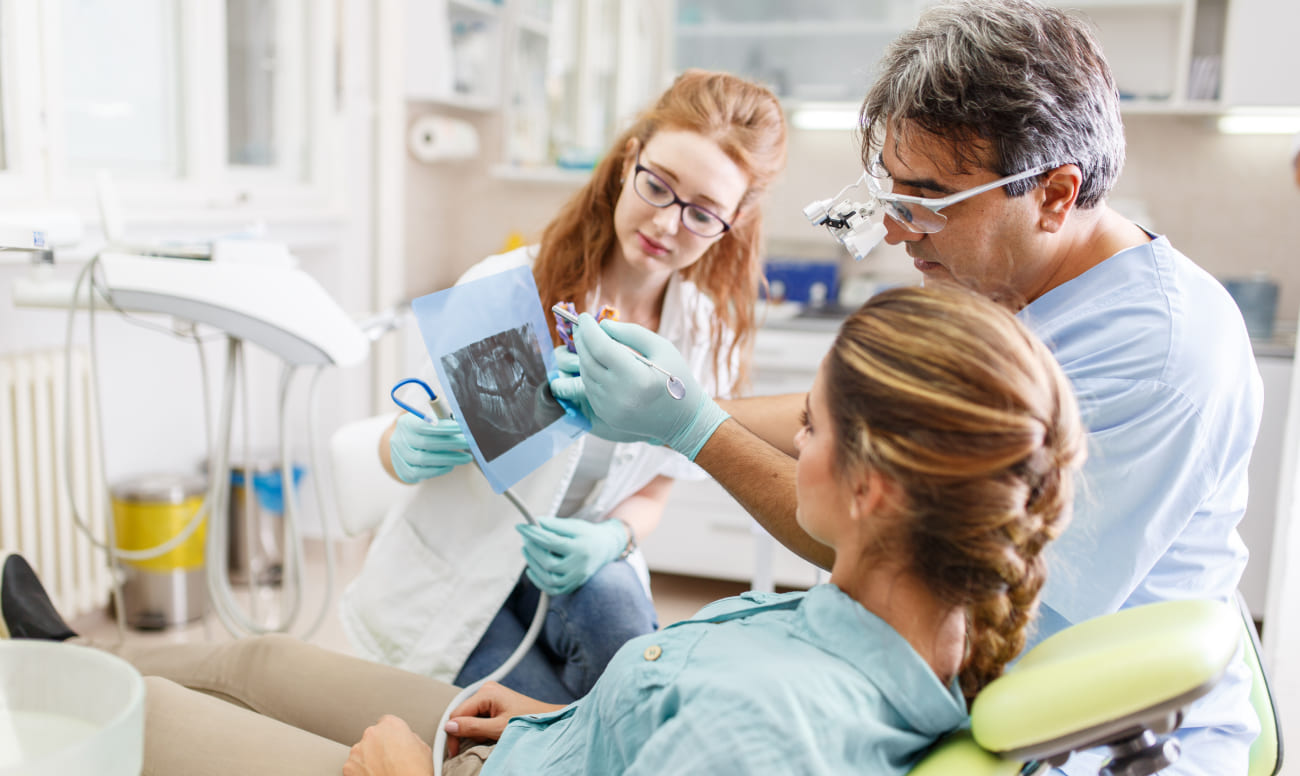 Фото пациентки на приеме у стоматолога, который проводит диагностику перед трансплантацией зуба