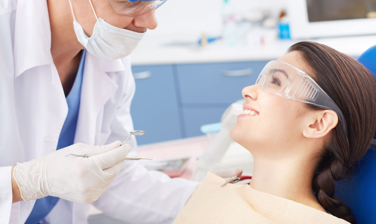 Фото улыбающейся девушки на приеме у стоматолога