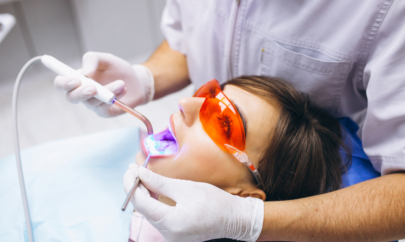 Фото пациентки на приеме во время профессионального отбеливания зубов.