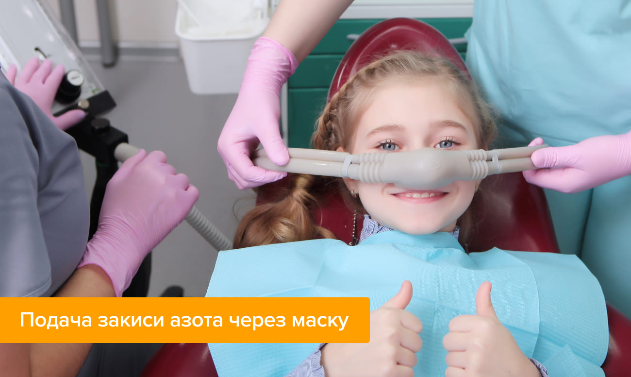 Фото маленькой пациентки в кресле стоматолога, с маской подающей закись азота на лице