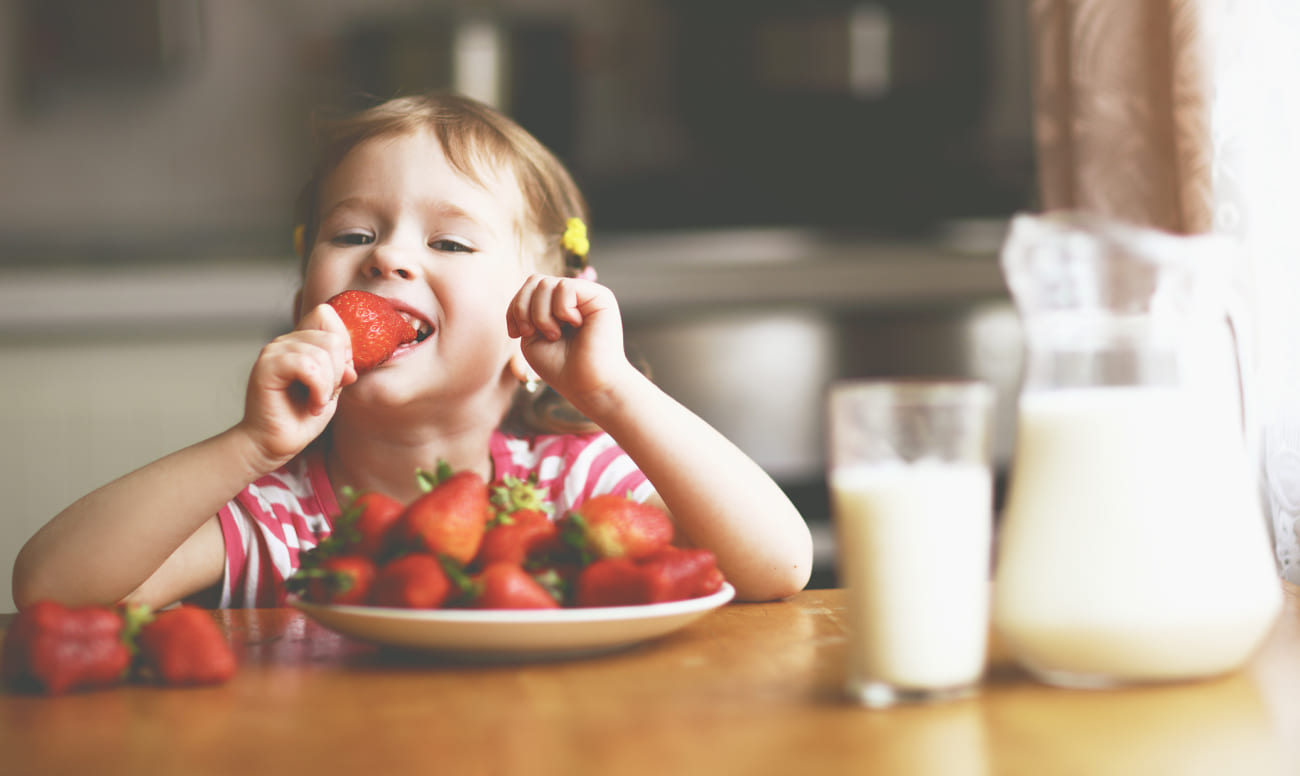 Фото ребенка, который кушает полезную для детских зубов клубнику