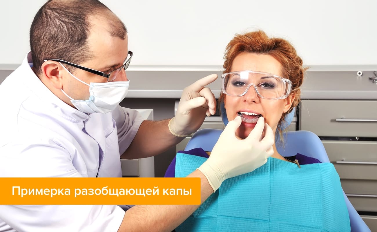 Примерка разобщающей капы Фото: девушка на приеме у стоматолога примеряет разобщающую капу
